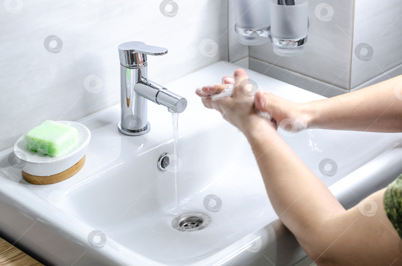 Скачать Мытье рук с мылом. Профилактические меры против заражения. Молодой парень моет руки с мылом в ванной. Гигиена тела. Борьба с COVID-19. фотосток Ozero