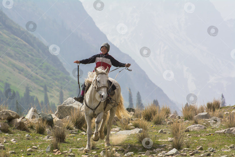 Скачать 7-летний кыргызский мальчик катается на лошади в горах Кыргызстана фотосток Ozero