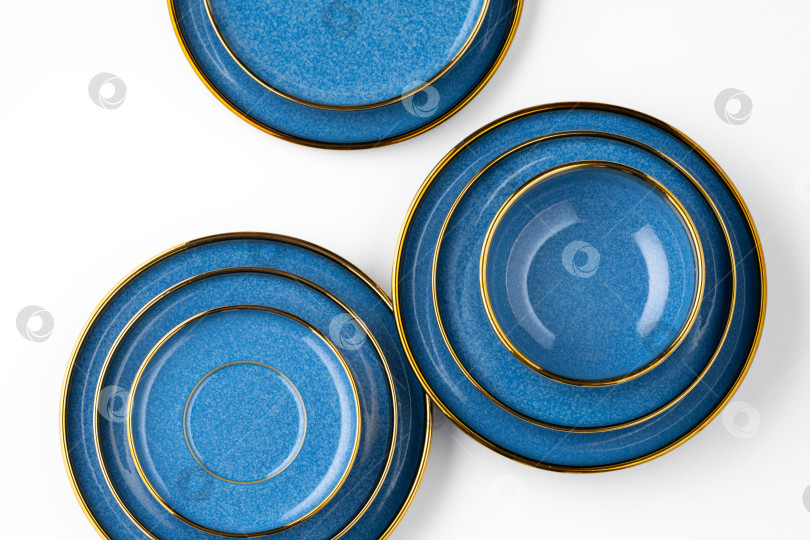 Скачать Набор синих керамических тарелок на белом фоне. Вид сверху фотосток Ozero