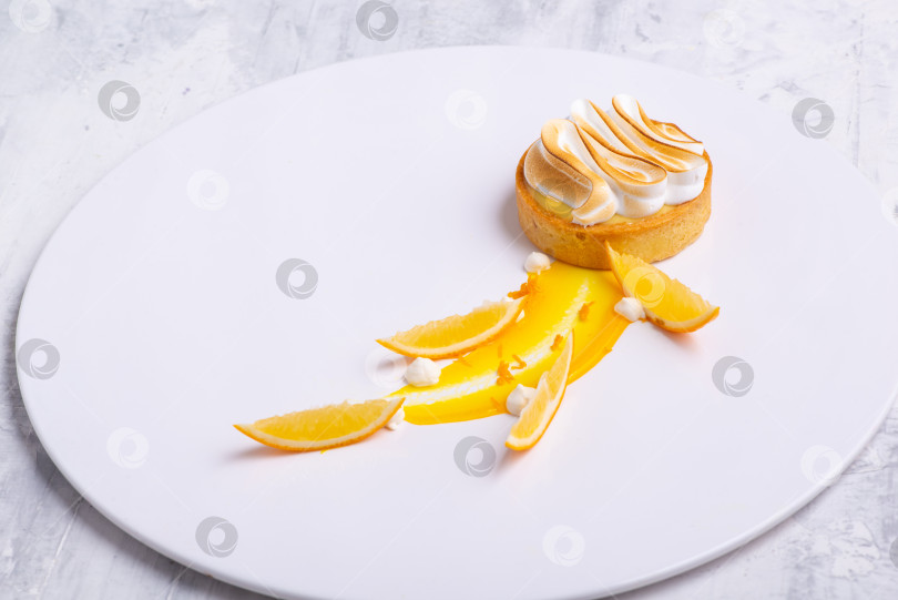 Скачать Аппетитные лимонные тарталетки с безе подаются на белом блюде фотосток Ozero