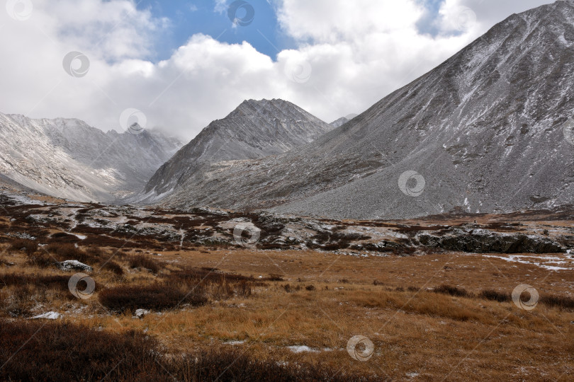 Скачать Долина между двумя горными хребтами, поросшая травой и мхом, под пасмурным осенним небом, припорошенная первым снегом. фотосток Ozero