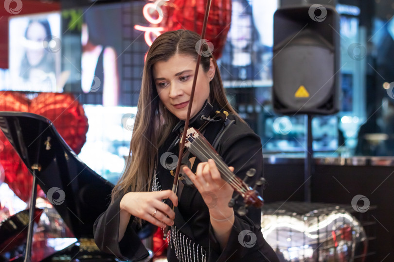 Скачать Беларусь, Минск - 07 февраля 2024 года: Симпатичная девушка играет на скрипке фотосток Ozero