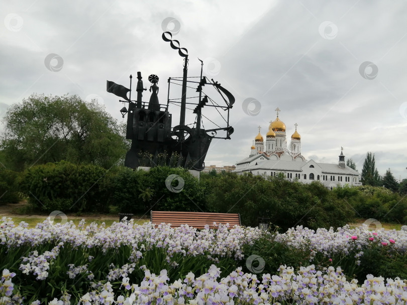 Скачать Цветущие ирисы на аллее с уникальной скульптурной композицией "Первый пароход" рядом с золотыми куполами церкви в городе Тольятти Самарской области фотосток Ozero