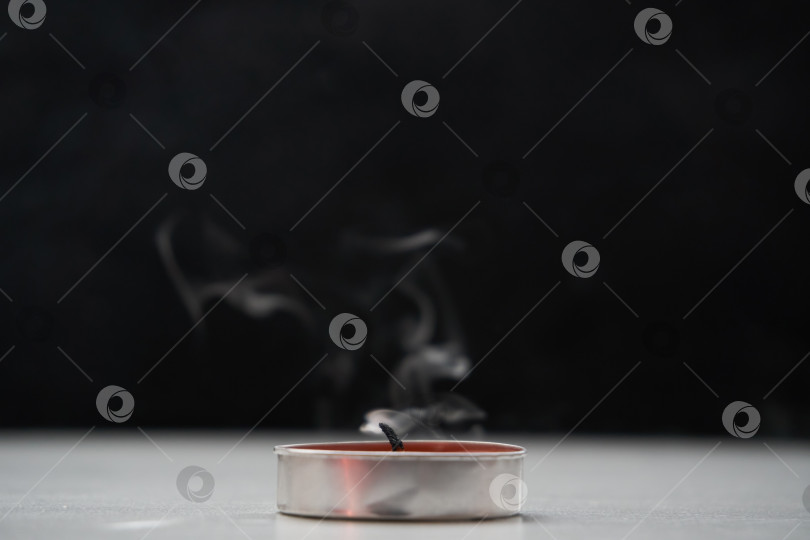Скачать Потушенная свеча, испускающая дым, стоит на столе на черном фоне. Мягкая избирательная фокусировка фотосток Ozero