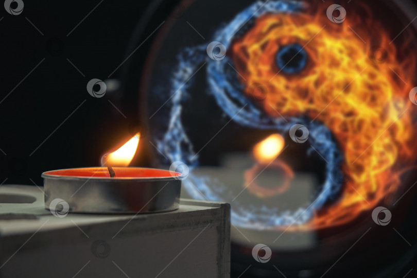 Скачать Сгоревшая свеча стоит на деревянной подставке на фоне зеркала, в котором изображены вода и огонь в форме инь-ян. Избирательный фокус фотосток Ozero
