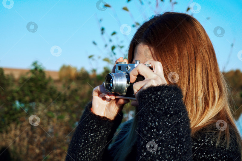 Скачать Девушка фотографирует природу кинокамерой. Осенняя погода, на улице. Избирательный избирательный фокус фотосток Ozero