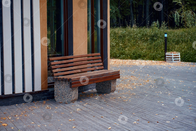 Скачать Рядом со зданием на брусчатке стоит деревянная скамейка с каменными ножками. Место для отдыха в парке фотосток Ozero