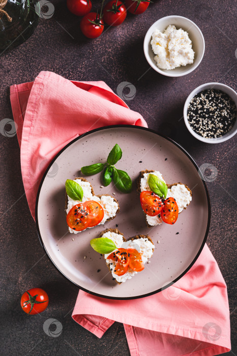 Скачать Бутерброды-сердечки с рикоттой и помидорами на ржаном хлебе на тарелке в вертикальном положении фотосток Ozero