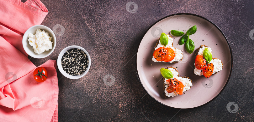 Скачать Бутерброды-сердечки с рикоттой и помидорами на ржаном хлебе на тарелке вид сверху веб-баннер фотосток Ozero