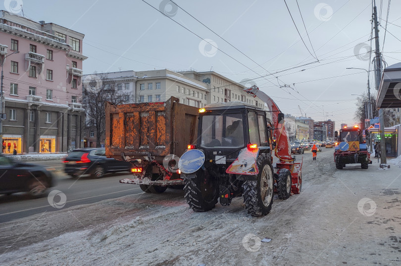 Скачать Уборка снега на городской улице. Снегоуборочная техника на центральной улице очищает остановку общественного транспорта. фотосток Ozero