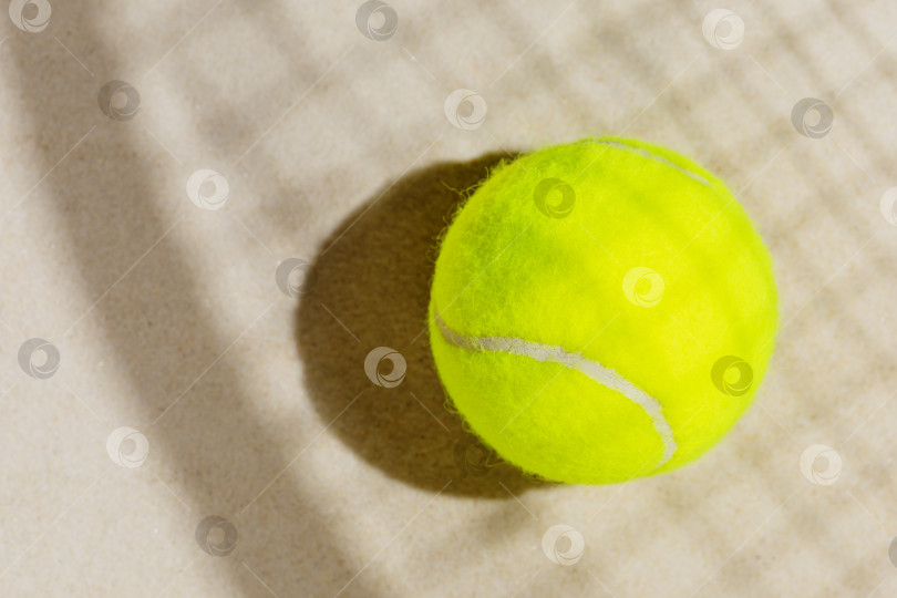 Скачать Теннисный желтый мяч на песчаном пляже с тенью от ракетки фотосток Ozero