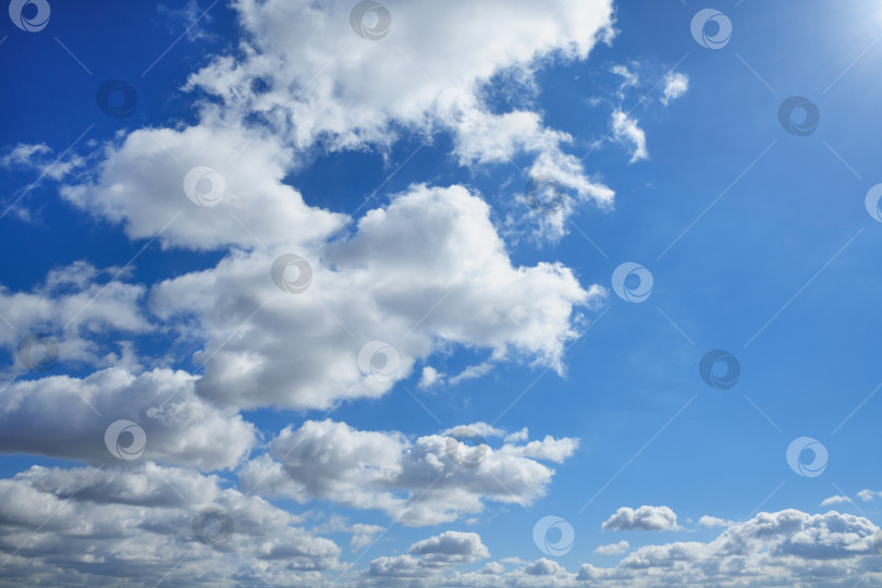 Скачать Пушистые облака в голубом небе, освещенные солнечным светом (фон) фотосток Ozero