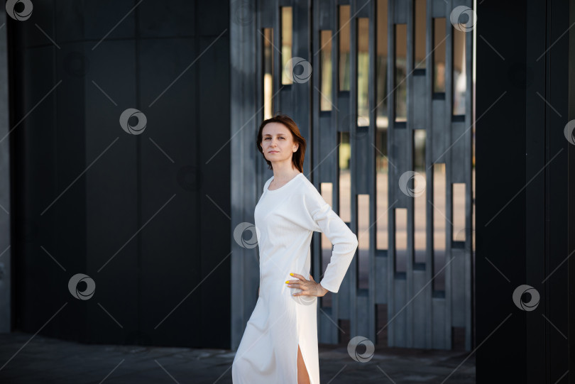 Скачать Молодая женщина в официальной одежде прогуливается возле серой стены на открытом воздухе, место для текста фотосток Ozero