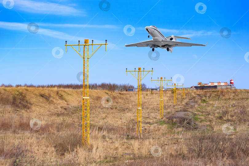 Скачать Самолет готовится к посадке, пролетая над металлическими опорами с навигационными сигнальными огнями фотосток Ozero