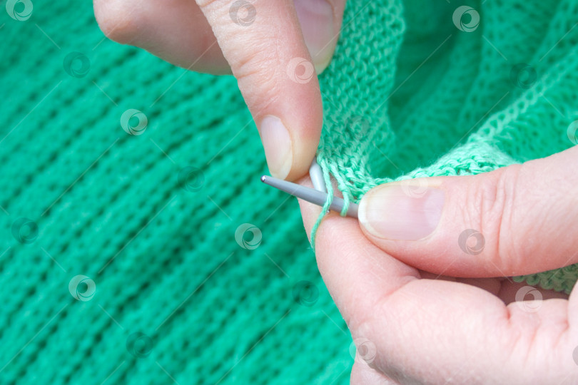 Скачать Крупный план рук пожилой женщины, которая вяжет зеленый свитер фотосток Ozero