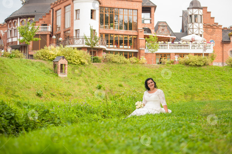 Скачать молодая невеста позирует, сидя на лужайке фотосток Ozero