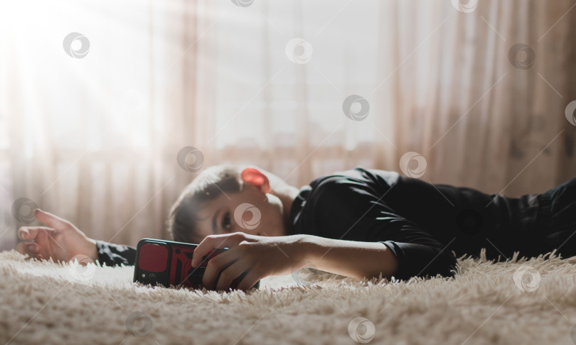 Скачать Изображение маленького мальчика в помещении, сидящего на диване с телефоном фотосток Ozero