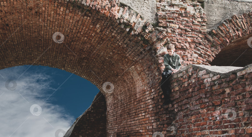 Скачать Маленький мальчик гуляет по парку рядом со старой крепостью фотосток Ozero