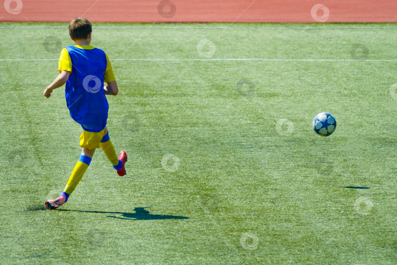 Скачать Футбольный матч, молодой игрок делает удар по мячу фотосток Ozero