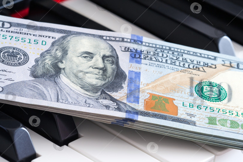 Скачать Крупный план стодолларовой банкноты на клавиатуре пианино (концепция) фотосток Ozero