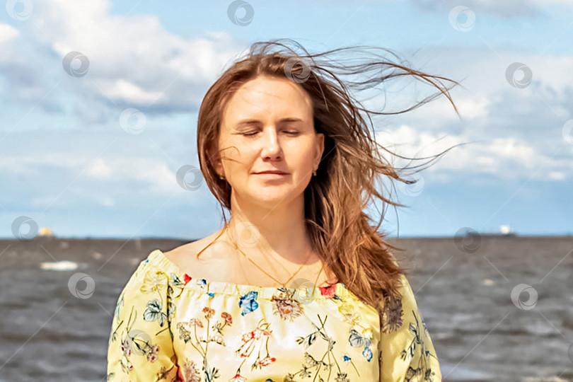 Скачать Большой портрет молодой женщины с развевающимися на ветру волосами на берегу моря фотосток Ozero