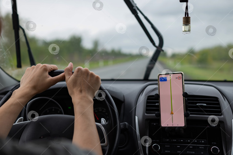 Скачать Вид сзади на юного путешественника, пользующегося навигатором на мобильном телефоне за рулем современного автомобиля. фотосток Ozero