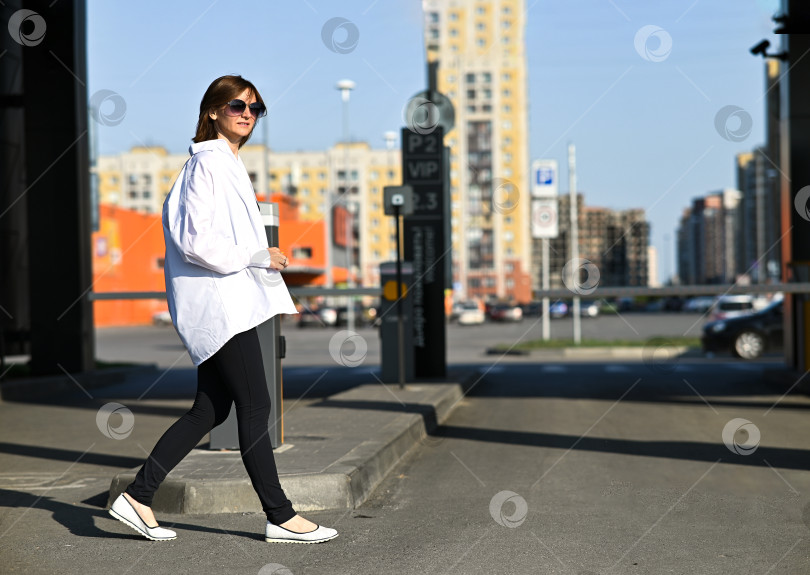 Скачать Молодая женщина в официальной одежде прогуливается возле серой стены на открытом воздухе, место для текста фотосток Ozero