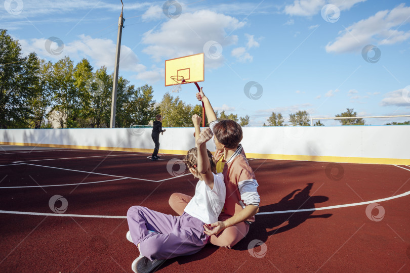 Скачать Цель. Эмоциональная женщина и девочка-подросток болеют за своего брата, сына или друга, маленький мальчик бросает баскетбольный мяч фотосток Ozero