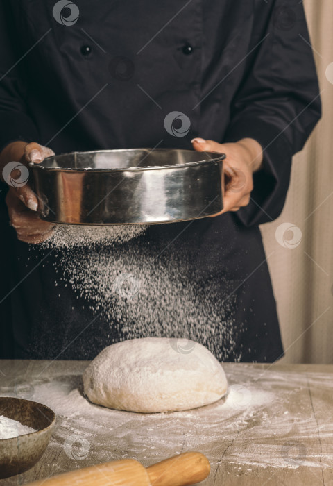 Скачать Женщина протирает тесто через сито крупным планом. Шеф-повар готовит тесто для торта, праздничного ужина фотосток Ozero