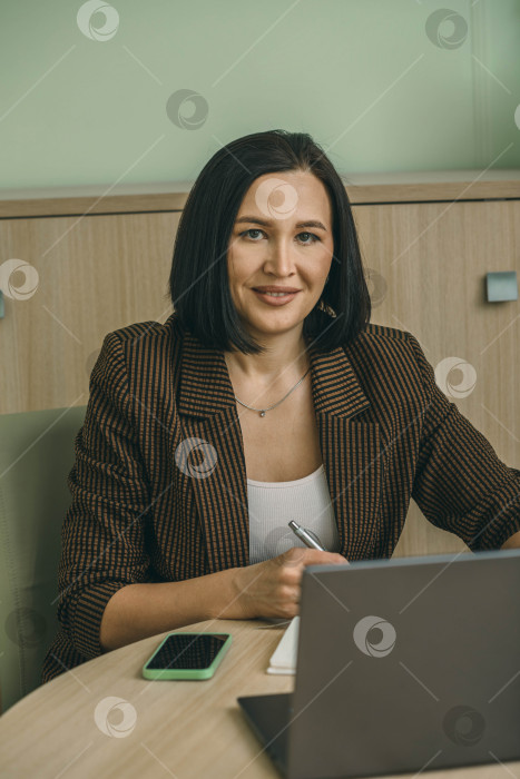 Скачать Счастливая деловая женщина, пользующаяся ноутбуком в современном офисе. Стильный, красивый, улыбающийся менеджер, работающий над финансовыми и маркетинговыми проектами фотосток Ozero