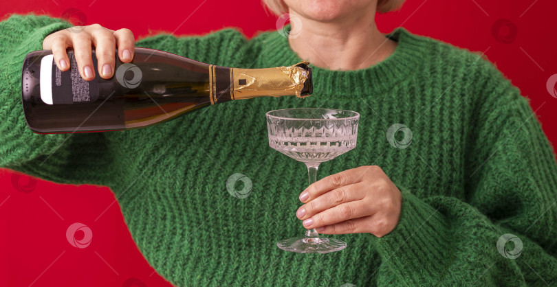 Скачать Концепция рождественской вечеринки: женщина в зеленом свитере наливает шампанское, вино в бокал. Праздничный фон рождественской вечеринки фотосток Ozero