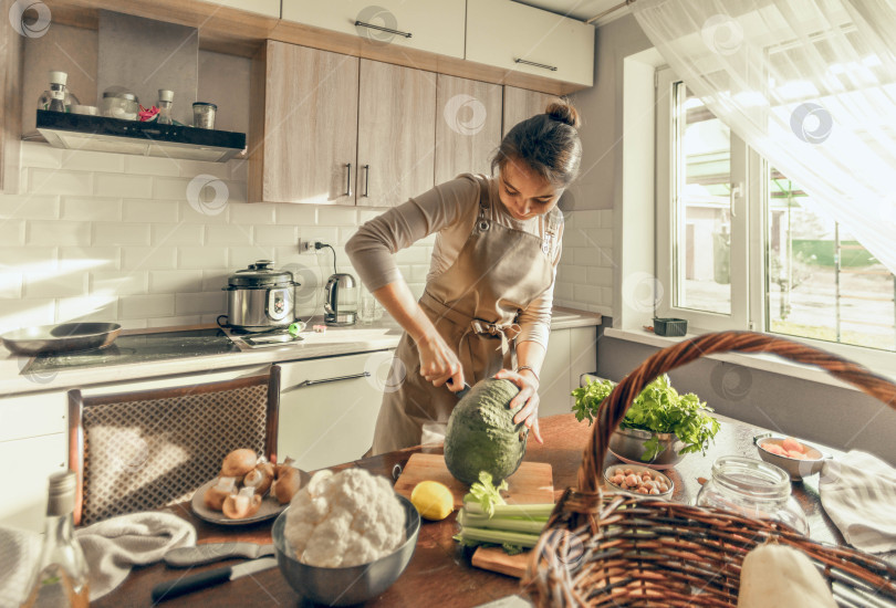 Скачать Молодая женщина режет тыкву ножом на кухне. Концепция здорового питания фотосток Ozero