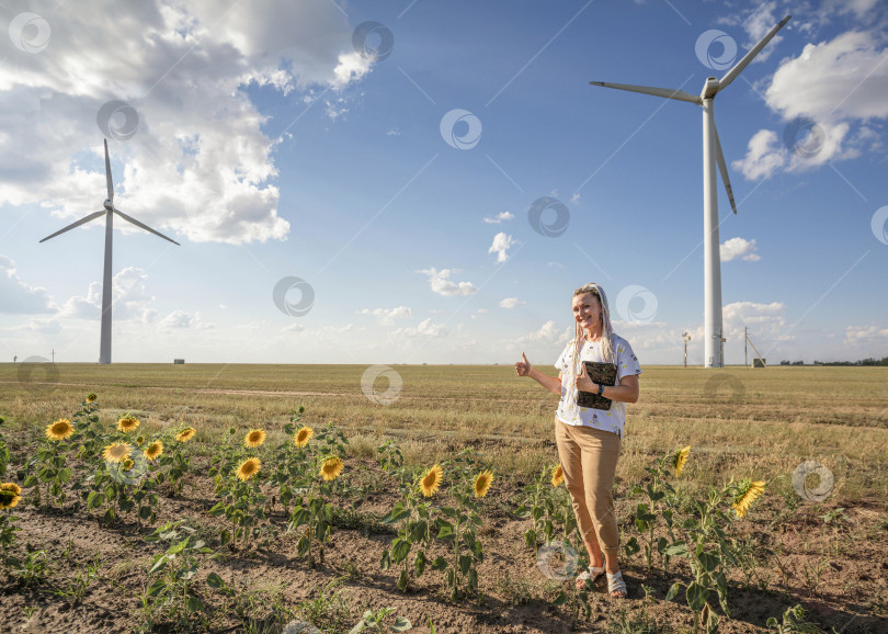 Скачать улыбчивая девушка-блогер с яркими косичками снимает сюжет о зеленой энергетике, о работе с энергией ветра и ветряными турбинами фотосток Ozero