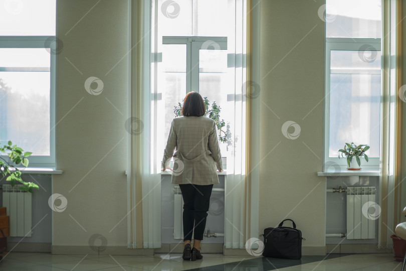 Скачать Неузнаваемая профессиональная бизнесвумен в холле офиса. бизнесвумен средних лет, руководящая сотрудница, стоит в рабочем вестибюле и смотрит в окно. фотосток Ozero