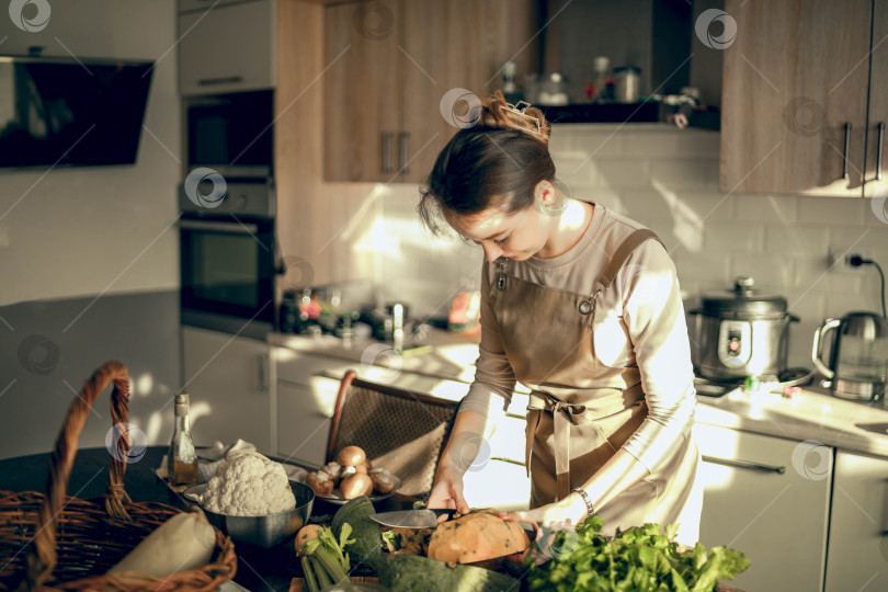 Скачать Снимок спортивной женщины, режущей тыкву ножом для приготовления на кухне в домашних условиях фотосток Ozero