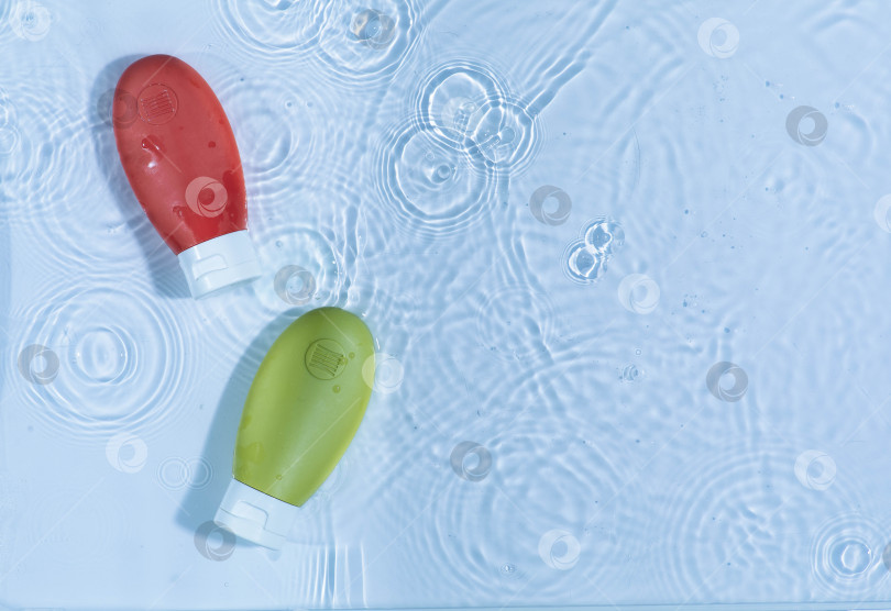 Скачать Макет небольшой упаковки косметики для путешествий: гиалуроновая кислота, мицеллярная эмульсия на фоне голубой воды с брызгами фотосток Ozero