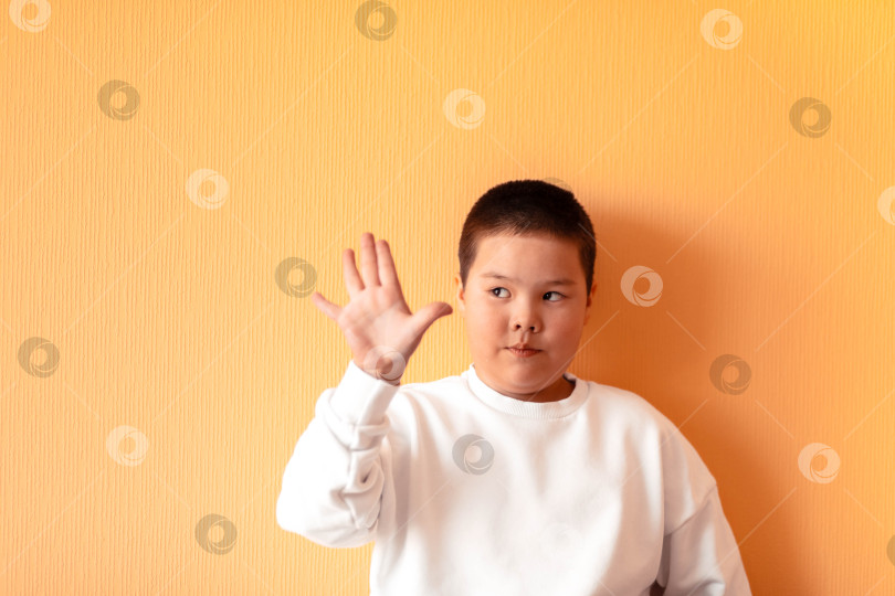 Скачать Юношеская волна: Невинность детства запечатлена в расслабленном и счастливом поведении мальчика, когда он приветственно машет рукой. фотосток Ozero