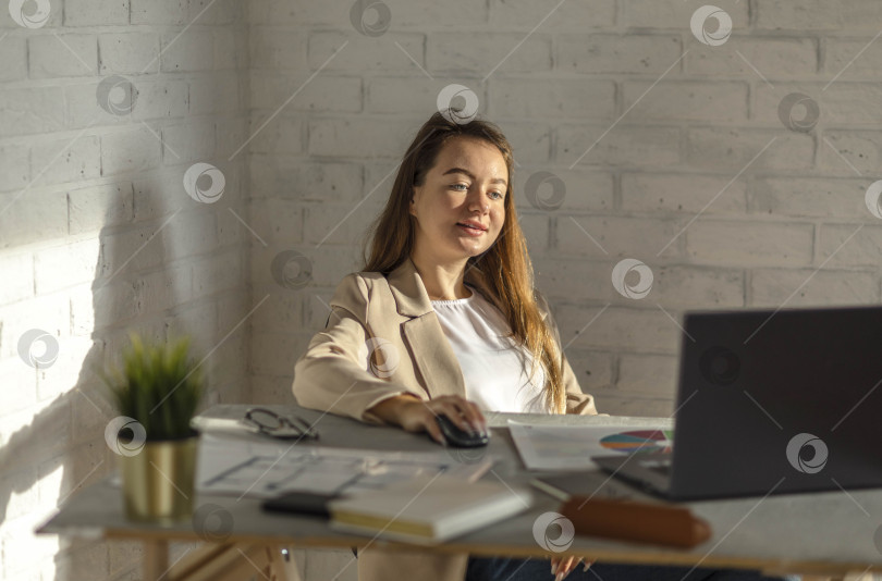 Скачать снимок успеха: энергичная молодая бизнесвумен улыбается, полностью погруженная в свою работу в современном офисе фотосток Ozero