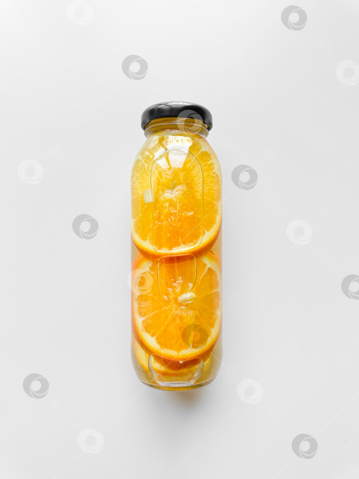 Скачать Детокс-напиток с дольками апельсина во внутренней стеклянной бутылке, выделенный на белом фоне. Вид под высоким углом с возможностью копирования. Концепция свежести и увлажнения для дизайна, направленного на улучшение здоровья и самочувствия. фотосток Ozero