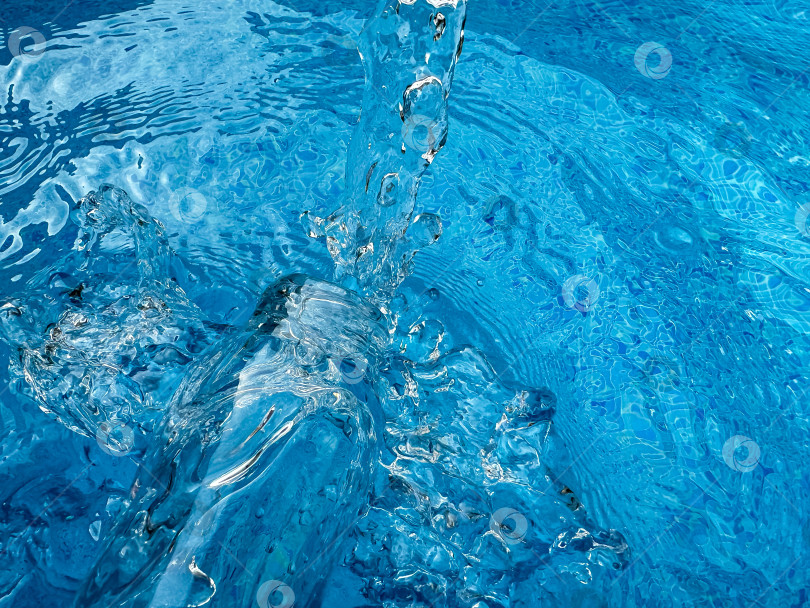 Скачать Динамичный всплеск кристально чистой голубой воды в стеклянной бутылке, создающий рябь и движущиеся капли воды. Концепция чистой воды. фотосток Ozero