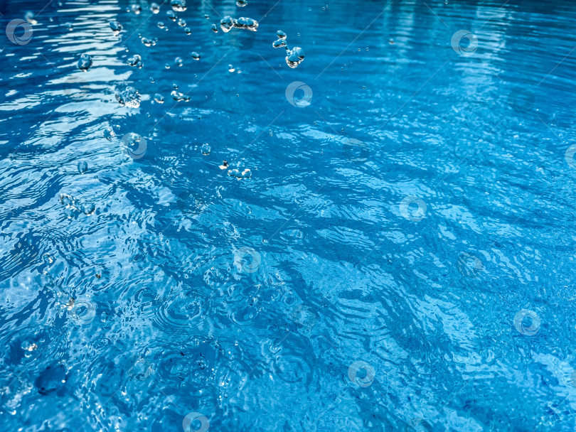 Скачать Фон: динамичный всплеск чистой воды, создающий крутящуюся волну в голубой воде с подвешенными в движении капельками. Концепция чистой воды. фотосток Ozero