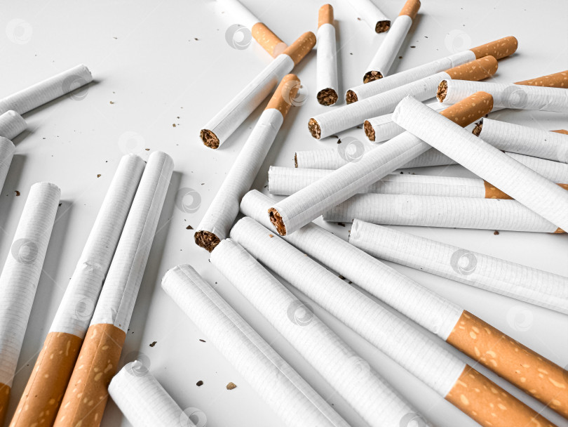 Скачать Разбросанные незажженные сигареты создают хаотичный узор на белом фоне, символизирующий отказ от курения и табачной зависимости. День без табака. фотосток Ozero