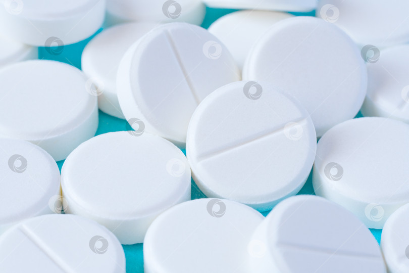 Скачать Крупный план горки белых круглых таблеток на бирюзовом столе в качестве фона (макрос) фотосток Ozero
