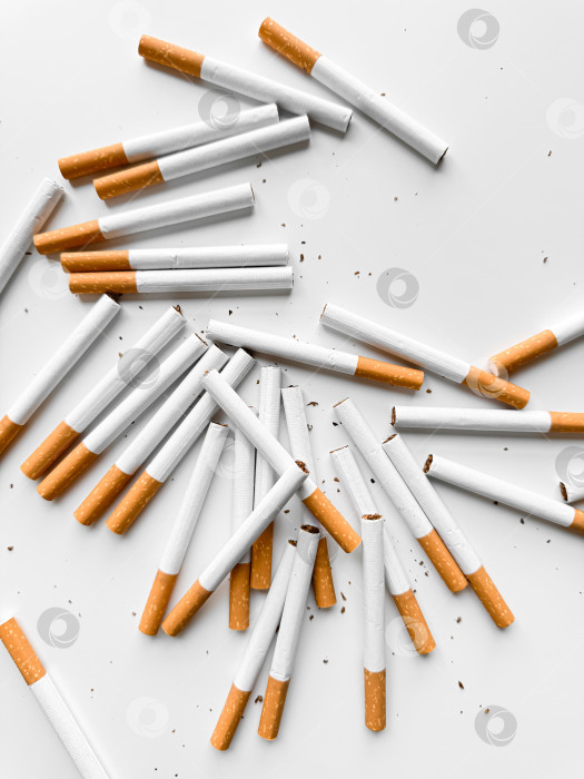Скачать Разбросанные незажженные сигареты создают хаотичный узор на белом фоне, символизирующий отказ от курения и табачной зависимости. День без табака. фотосток Ozero