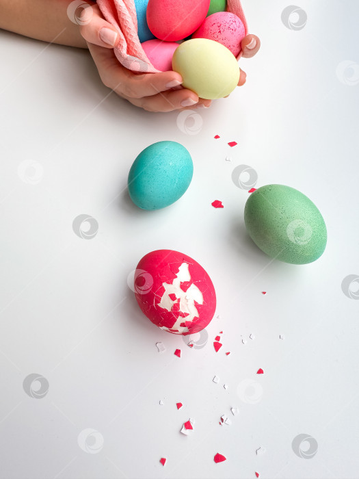 Скачать Руки, держащие разноцветные расписные пасхальные яйца с одним треснувшим яйцом сбоку, символизируют пасхальные торжества, весенние гуляния и семейные развлечения. фотосток Ozero