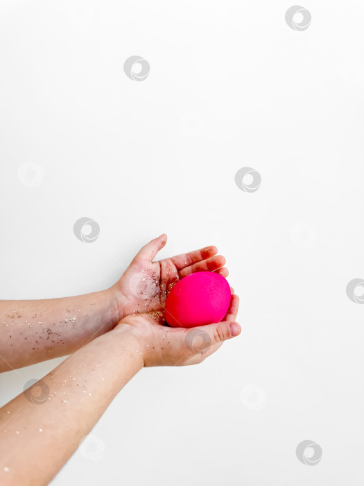 Скачать Руки, держащие розовое яйцо с блестками, концепция приготовления к Пасхе и праздничного мероприятия на белом фоне с возможностью копирования. Для креативного контента на пасхальную тематику и идей для семейного досуга. фотосток Ozero