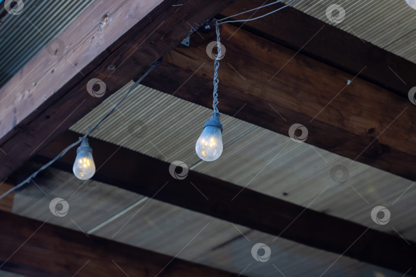 Скачать С деревянной балки свисают светильники, отбрасывающие теплый свет фотосток Ozero
