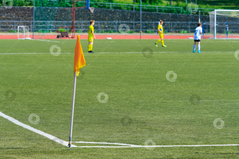 Скачать Желтый угловой флаг на футбольном поле против игроков в размытом виде фотосток Ozero