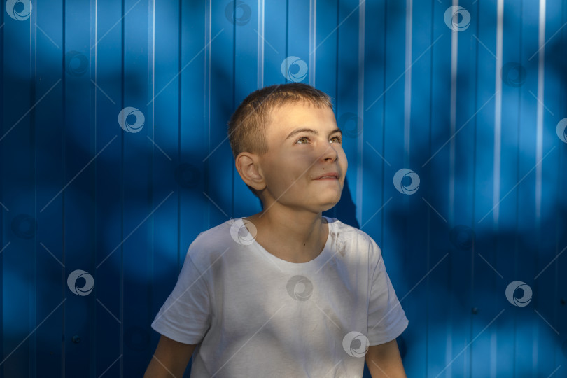 Скачать Мечты на горизонте: Полный надежды взгляд мальчика на фоне Голубой стены. фотосток Ozero