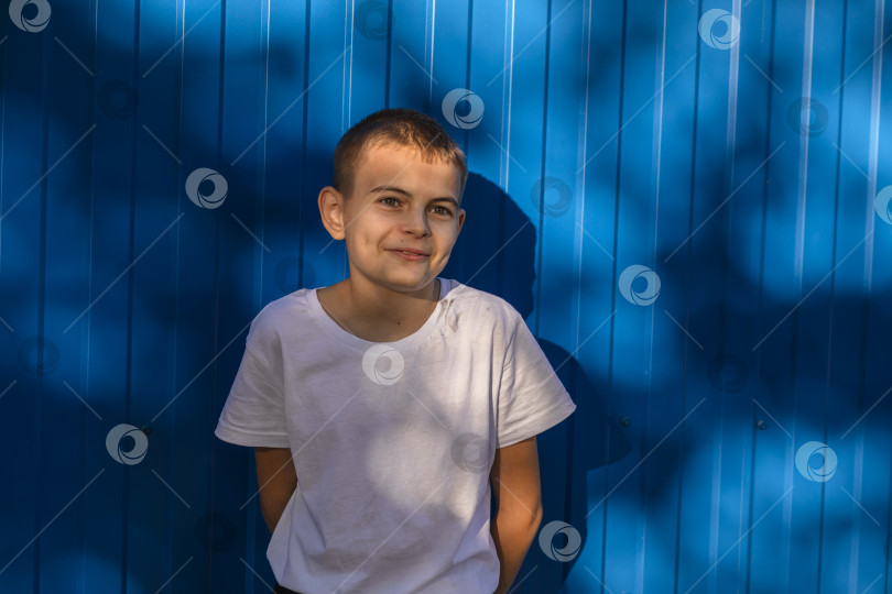 Скачать Безудержная радость: мальчик улыбается на фоне уличной голубой стены. фотосток Ozero